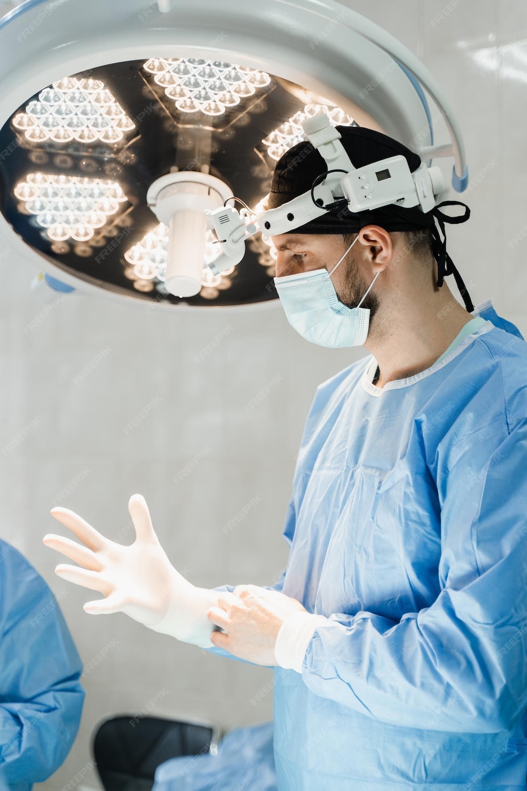 Chirurg. Gemeinschaftspraxis Dres. Peller & Bardenheuer Männlicher Chirurg zieht OP-Handschuhe an und desinfiziert vor der